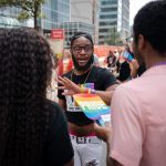 Johnny Wilson, an employee at the Mecklenburg County Health Department wearing a black shirt with a vaccine message, speaks with an individual about the Monkeypox vaccine at the 2022 Charlotte Pride Festival in uptown Charlotte, North Carolina on August 20, 2022.