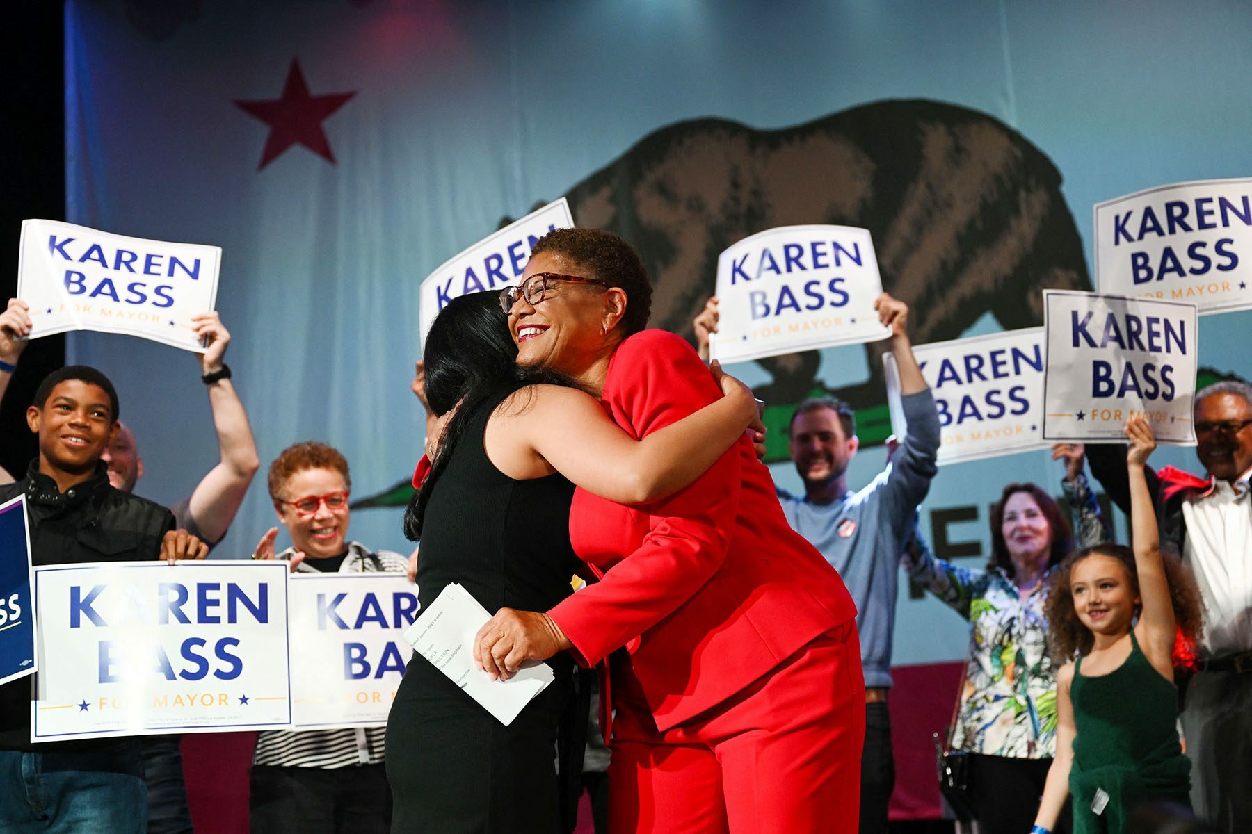 Karen Bass hugs her daughter as supporters holding 
