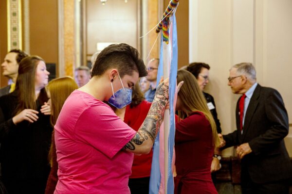 Becky Smith holds a transgender flag banner as Iowa Governor Kim Reynolds signs a bill which bans transgender girls from participating in girls sports at the Iowa State Capitol.