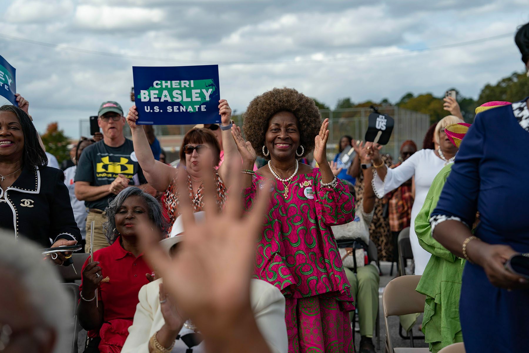 Cheri Beasley supporters smile, clap and cheer as she speaks at an event.