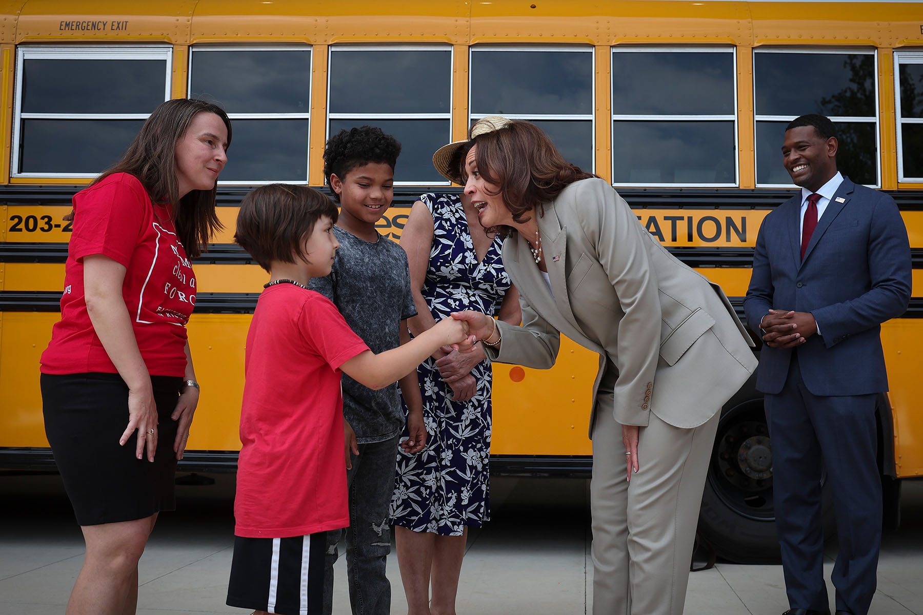 Vice President Kamala Harris greets young students while touring new electric powered school buses.