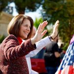 Catherine Cortez Masto waves to people as she sits on a trailer in a horse parade for Nevada Democrats.