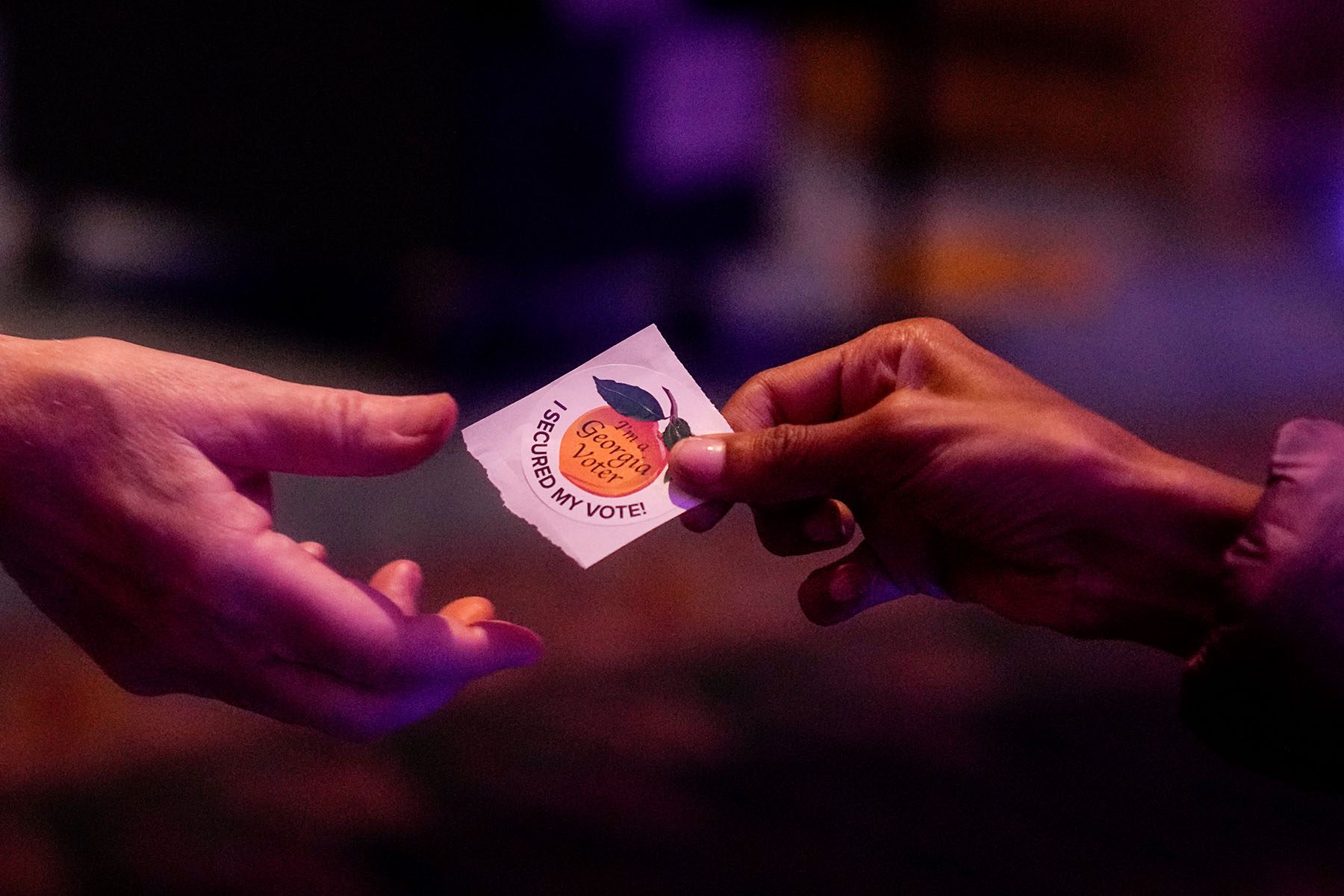 A poll worker hands off a sticker that reads "I'm a Georgia Voter" to a voter on Election Day in Atlanta.