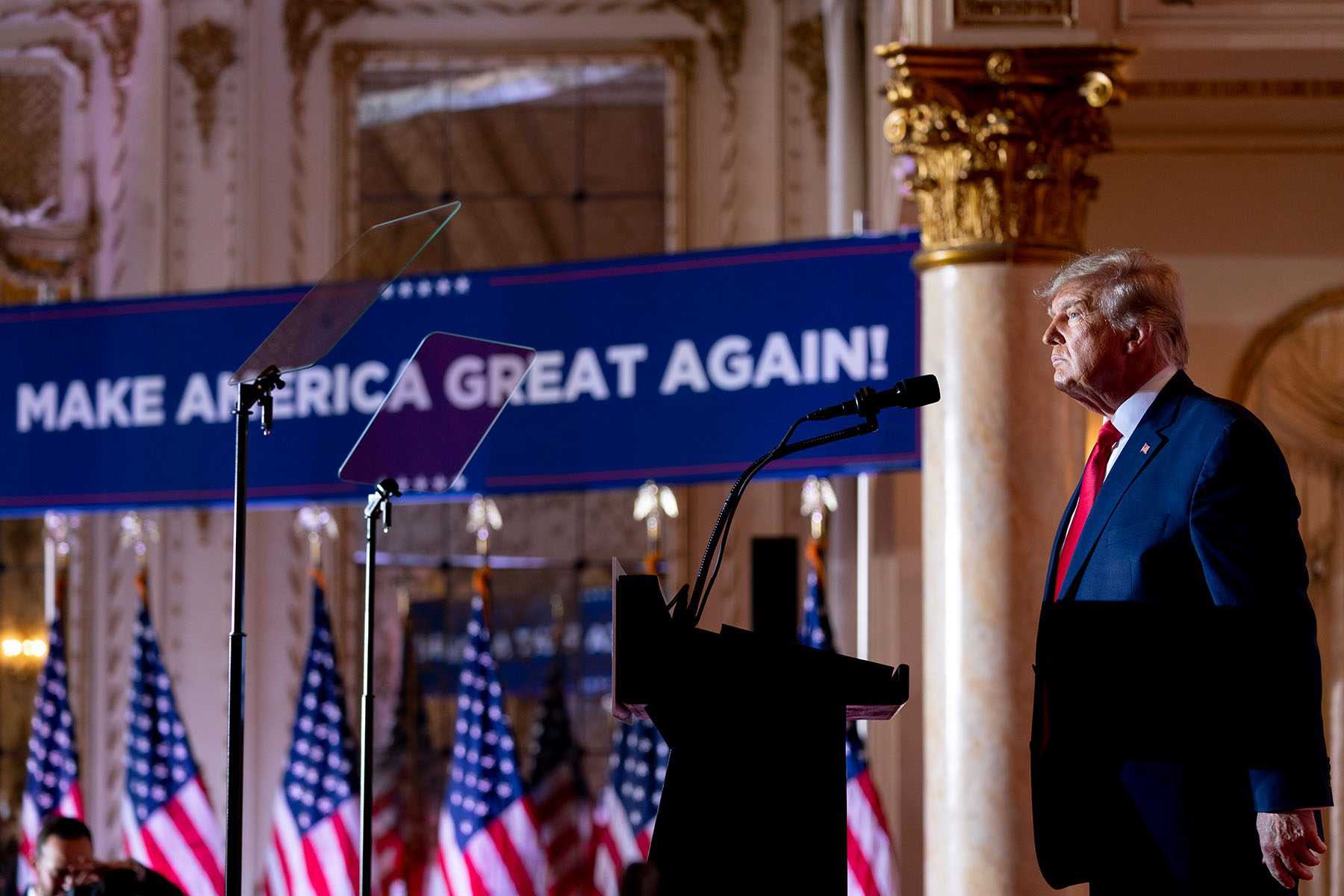 Former President Trump stands at a podium as he announces his third run for president. Behind him, a giant banner reads "Make American Great Again!"
