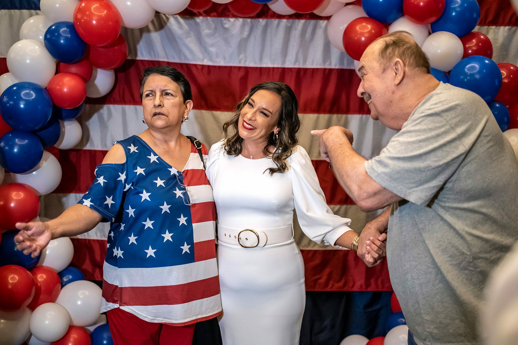 Monica De La Cruz and a supporter wearing an American flag shirt pose in front of red, white and blue balloons at her election night party.