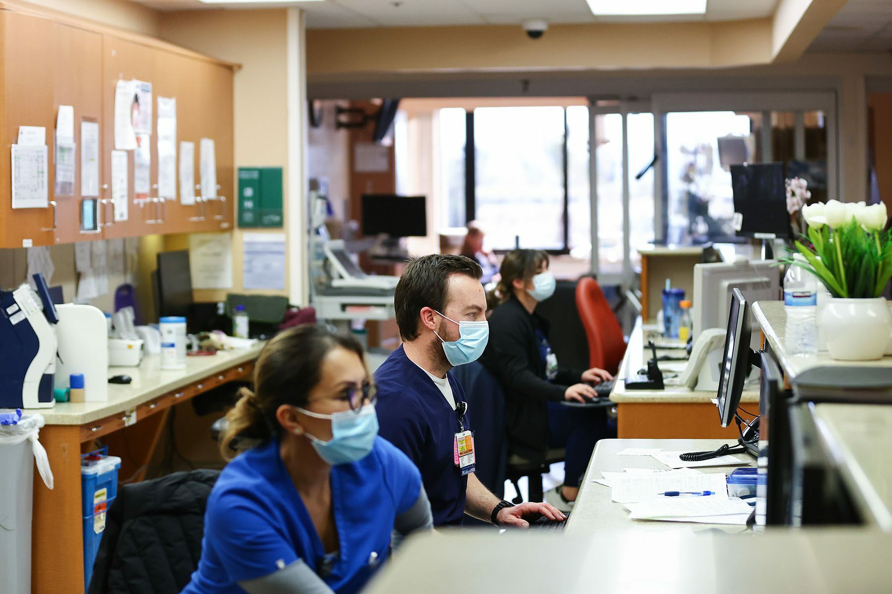 ICU nurses are seen working behind a reception desk.