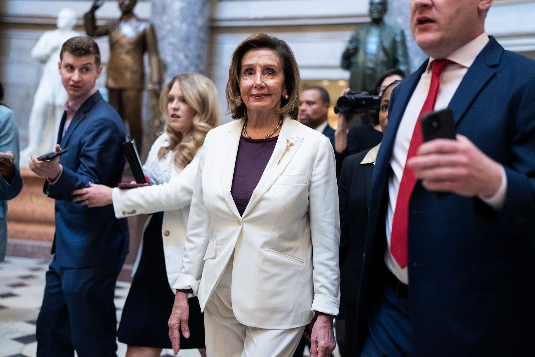 Nancy Pelosi, surrounded by staffers and reporters walk through the halls of Congress.