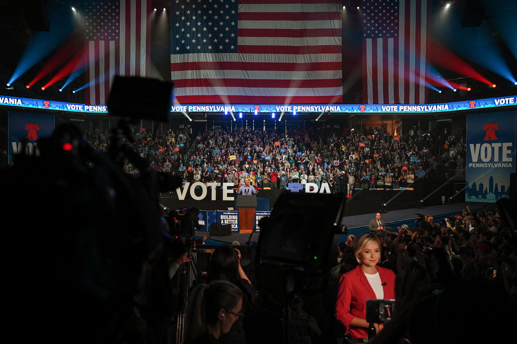 Former President Barack Obama speaks during a rally in support of Senate candidate John Fetterman. In the foreground, media is recording the event. In the background, supporters cheer and chant.