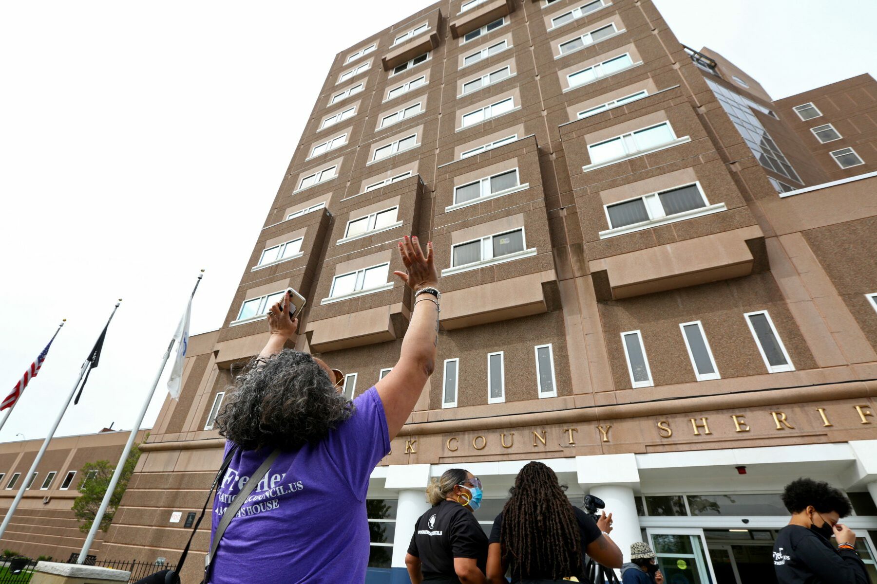 woman in purple shirt protesting outside Boston jail during COVID-19
