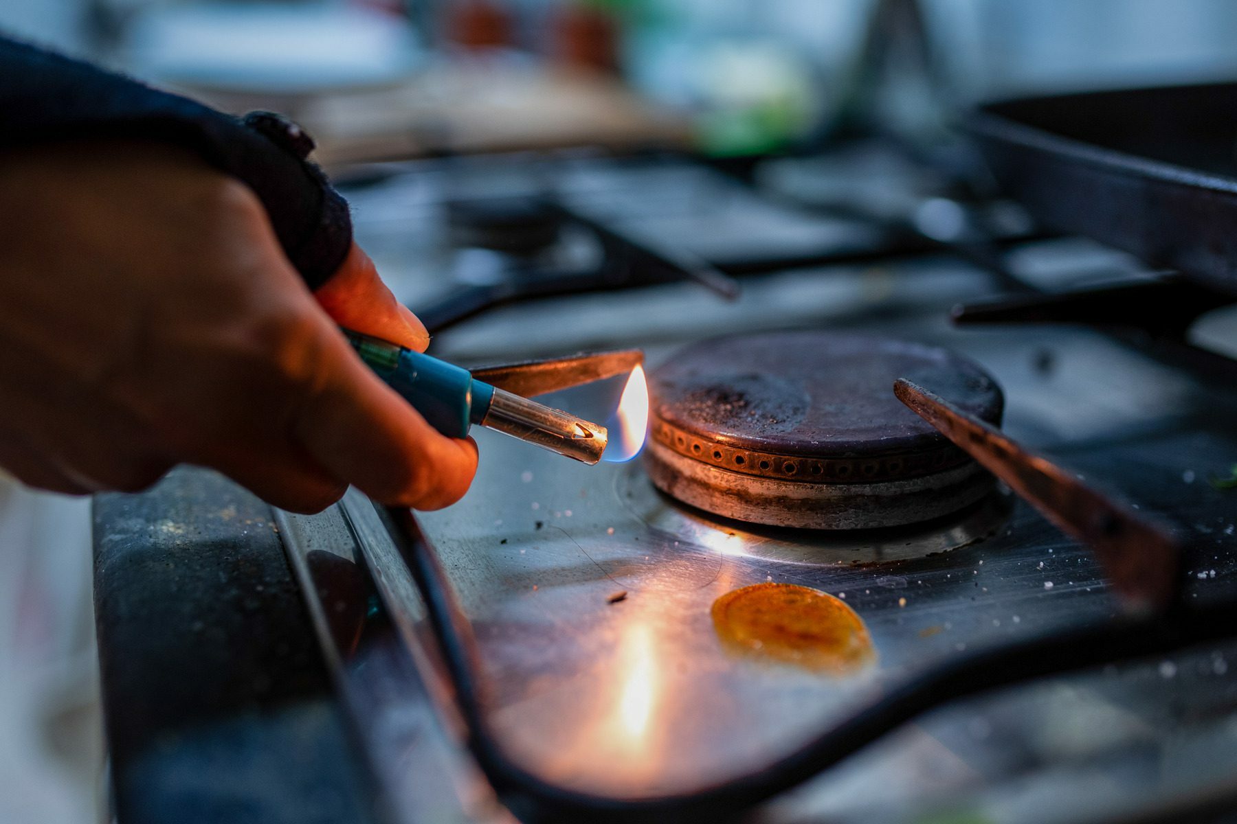 A person lights a gas burner inside a kitchen.