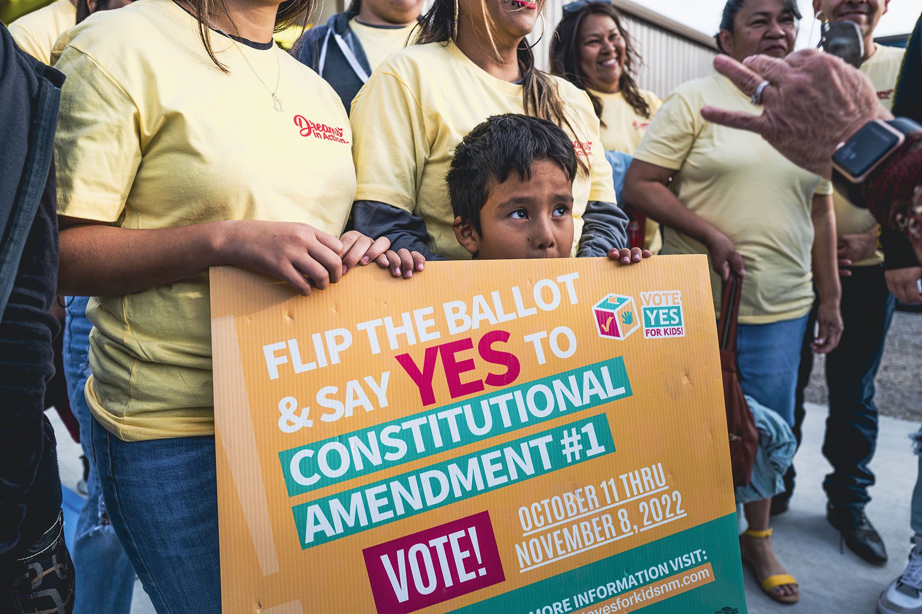 A child holds a sign that reads "Flip the ballor and say YES to constitutional amendment #1.