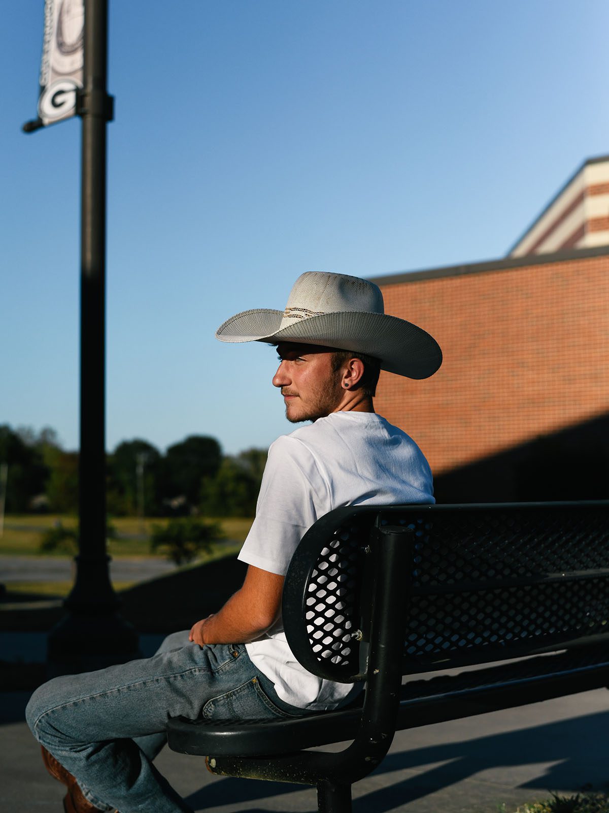 Dylan Brandt sits on a bench at golden hour as he poses for a portrait