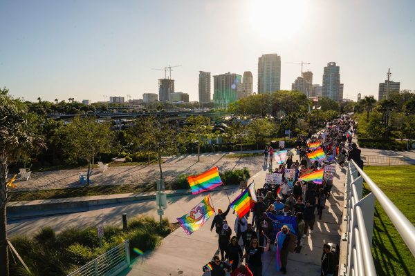 Demonstrators wave pride flags as they march across a bridge in protest of Florida's 