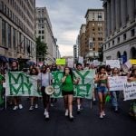 A large group of young abortion rights activists hold signs and banners as they march.