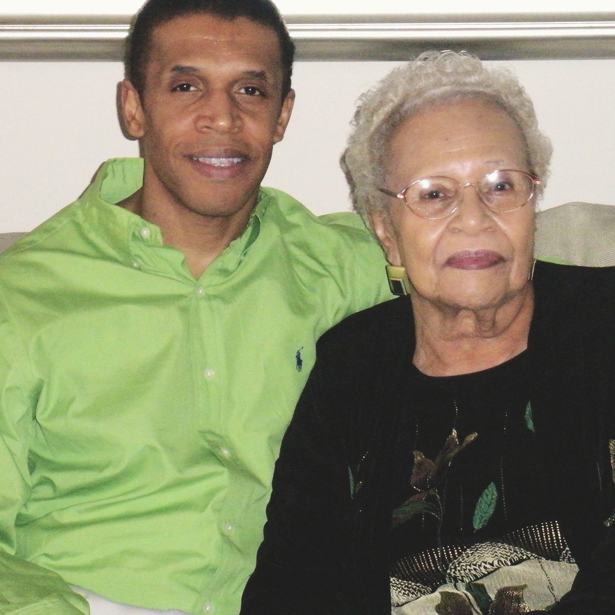 Harold Abrams hold his mother as they pose for a photo on a couch.