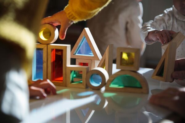 Small children play with colorful wooden building blocks on the table.