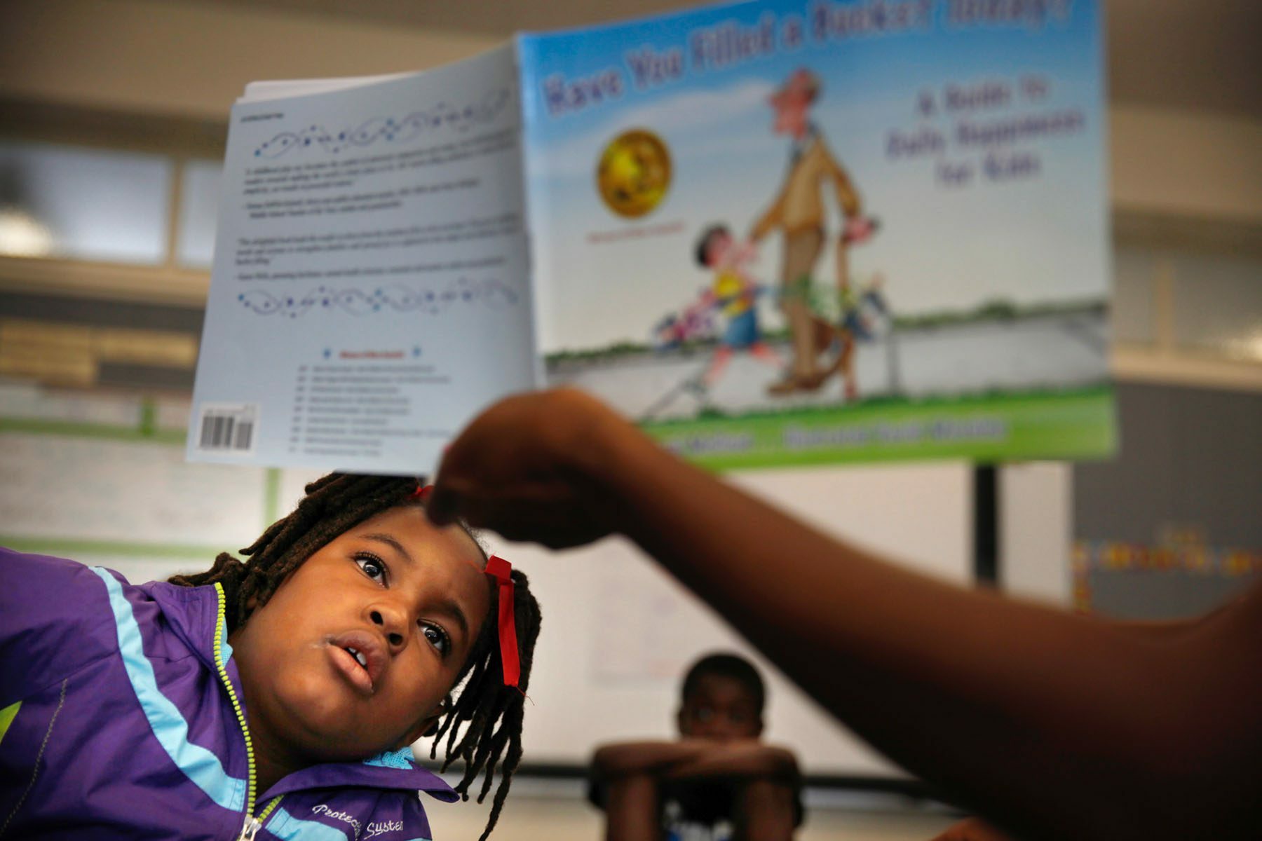 A student listens to a story being read by a teacher at the Children's Defense Fund's Freedom School Program site at West Oakland Middle School.