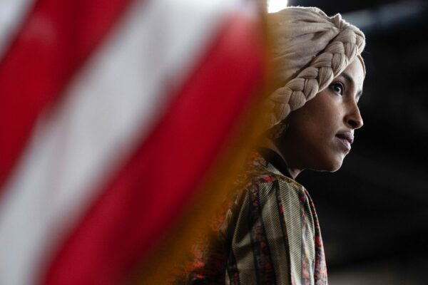 Rep. Ilhan Omar looks on near an American flag during a news conference.