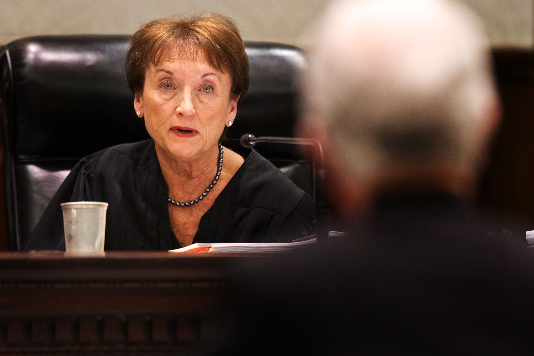 South Carolina Supreme Court Justice Kaye Hearn. She is sitting and speaking to a man whose back is turned to the camera in the foreground.