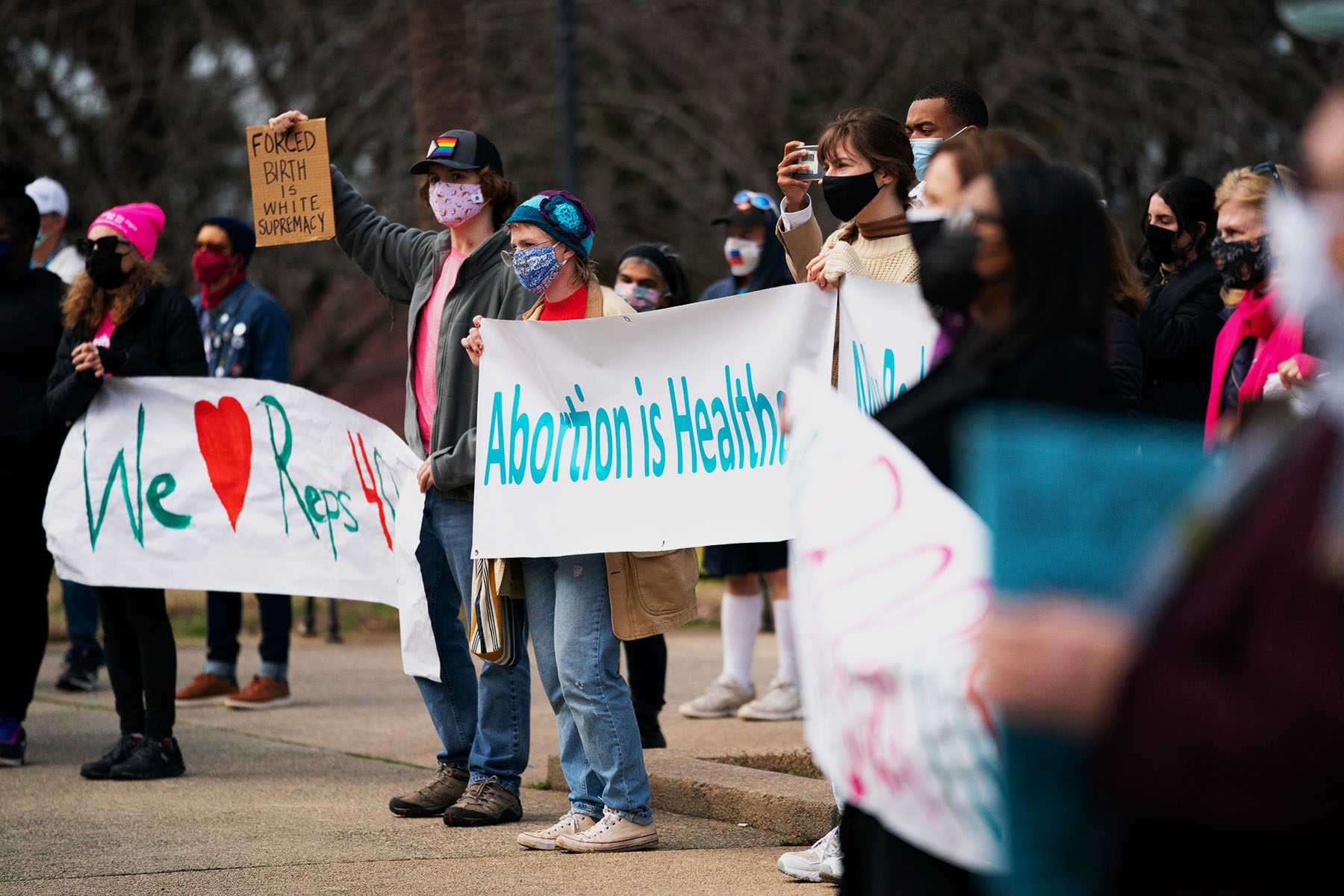 Demonstrators hold signs during a protest against an anti-abortion bill. The signs read "Abortion is Healthcare" and "Forced Birth is White Supremacy."