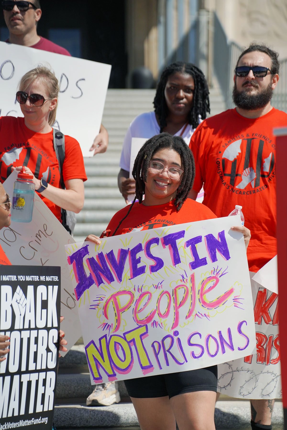Cameron Dumas holds a sign that reads "Invest in people, not prisons" at a rally advocating for the closing of youth prisons.