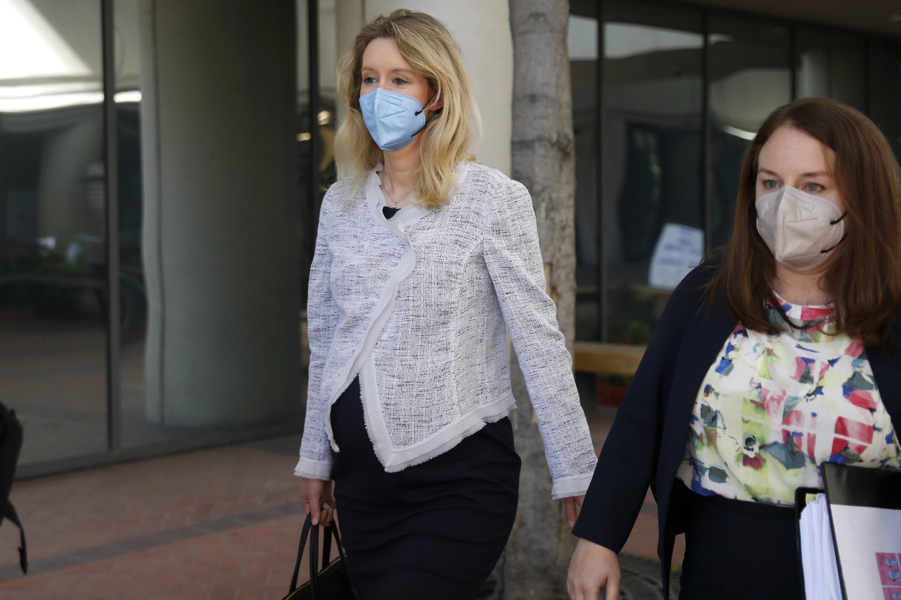 Theranos founder Elizabeth Holmes, pregnant with her first child, leaves the Robert F. Peckham Federal Building with her defense team in downtown San Jose, California in May 2021.