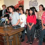 Julie Su, surrounded by Thai workers, announces that she is filing a Federal lawsuit against garment contractors on behalf of 62 Thai immigrants in September 1995.