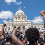 Supporters raise their fists while standing at the State Capitol during a National Mother's March.