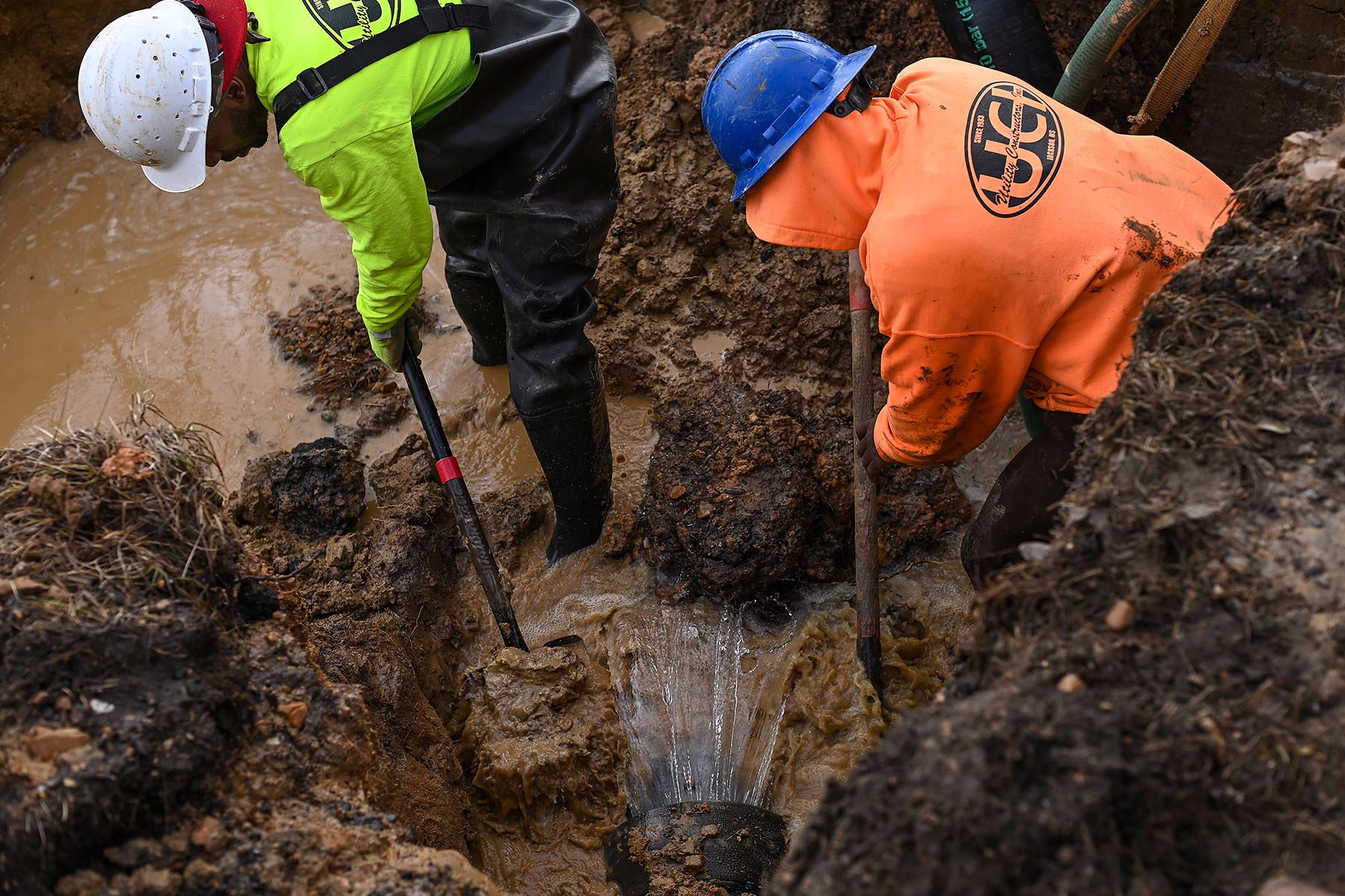 Workers shovel mud as they fix a damaged water main break along McLaurin Road in Jackson, Mississippi.
