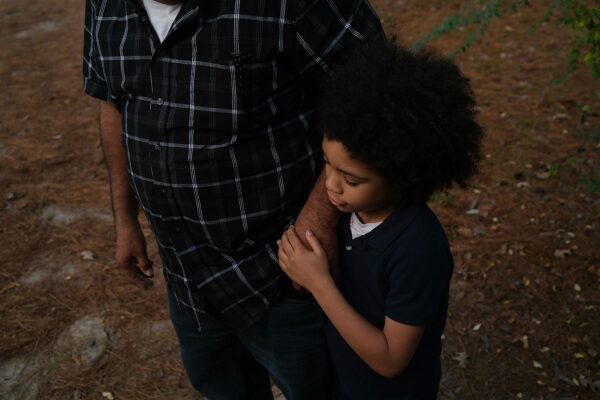 A father holds his son's hand outside their home in Jackson, Mississippi.