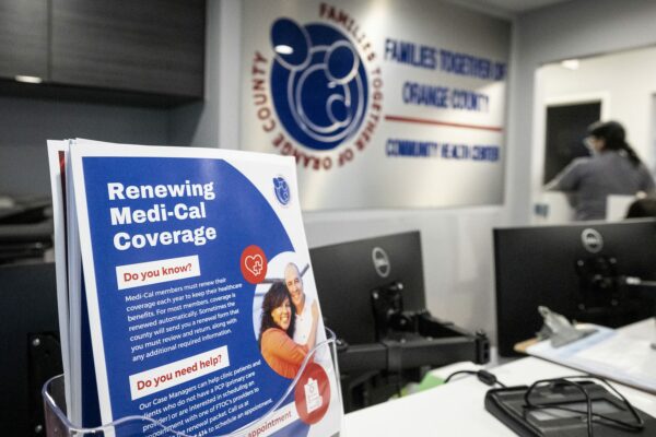 A front desk at a community health center with a sign about Medi-Cal medical coverage.