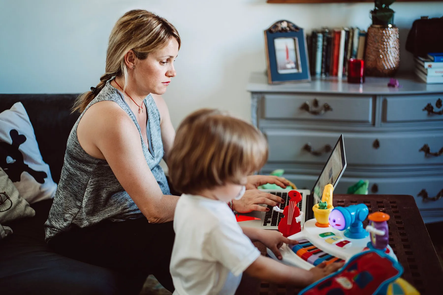 Woman working from home while her son plays next to her.