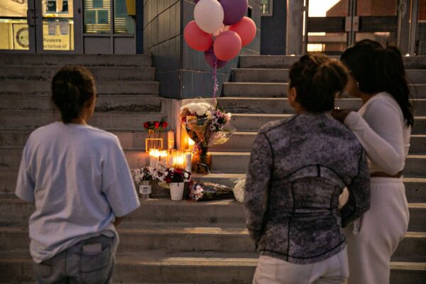 Students and community members pay their respects by placing flowers and candles on the steps of Helen Bernstein High School.