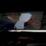 A dark image of biden seen inside the presidential limousine from outside the car's window.