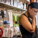 Business owner Lynn Gooden looks tired and frustrated as she takes a pause during work at her business, Mother's Hair Beauty Supply.