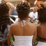 Three Black women with their back facing the camera and their unique hairstyles featured.