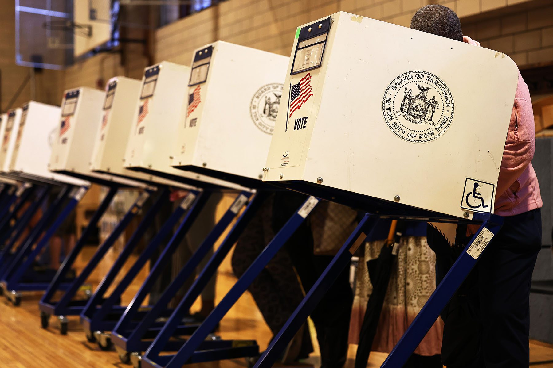 Voters stand behind covered ballot boxes while they vote.
