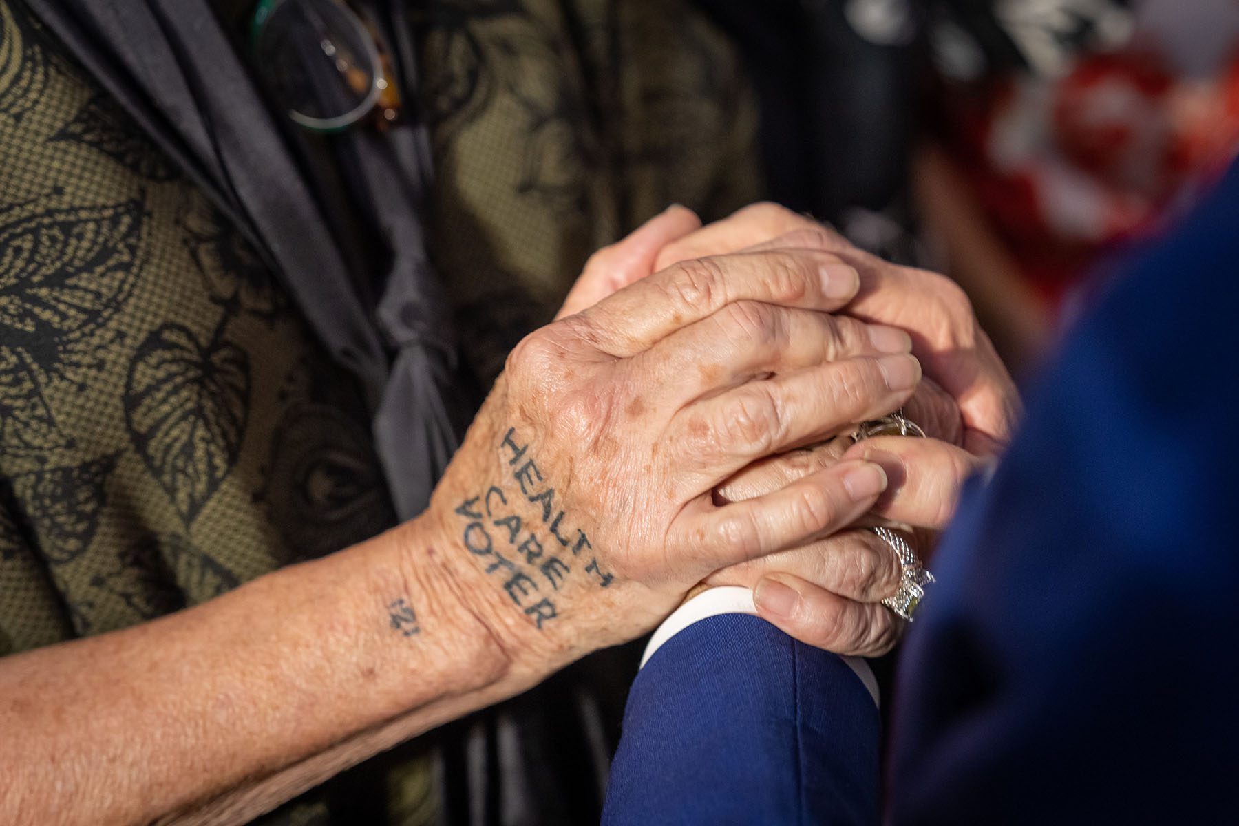 A detail shot of President Biden holding an attendees hand on which is written "health care voter" after an event at the University of Tampa, Florida.