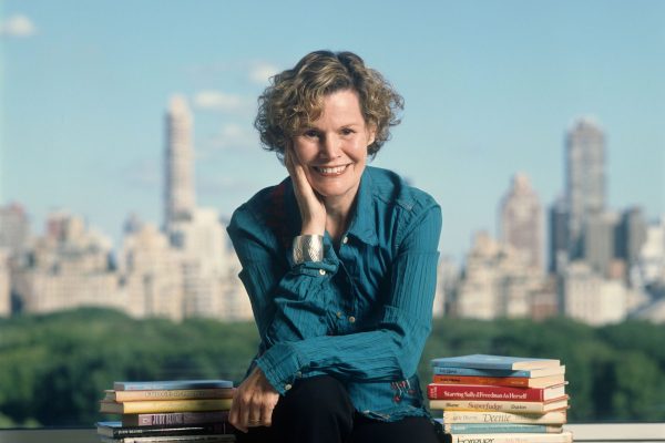Judy Blume poses for a portrait in New York City in 2006. She is surrounded by books she's written. Behind her, the New York City skyline is seen.