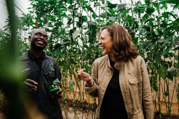 Kamala Harris laughs with a farmer while visting Panuka Farm just outside the city of Lusaka, Zambia.