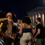 Two protesters hug each other during a candlelight vigil in front of the Supreme Court.