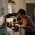 An older woman prepares a family dinner in her apartment.