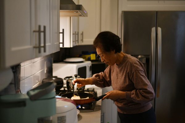An older woman prepares a family dinner in her apartment.