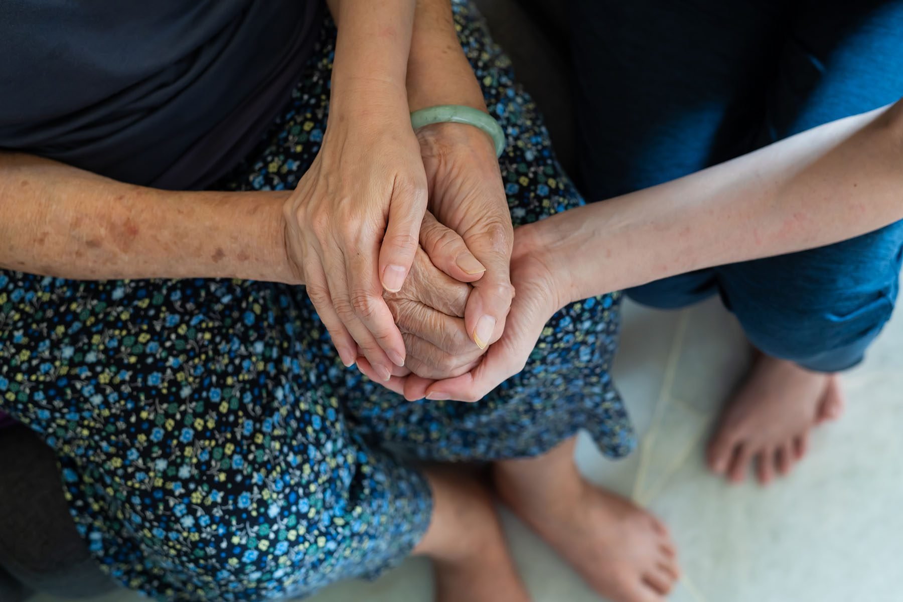 A daughter holds her elderly mother's hands.