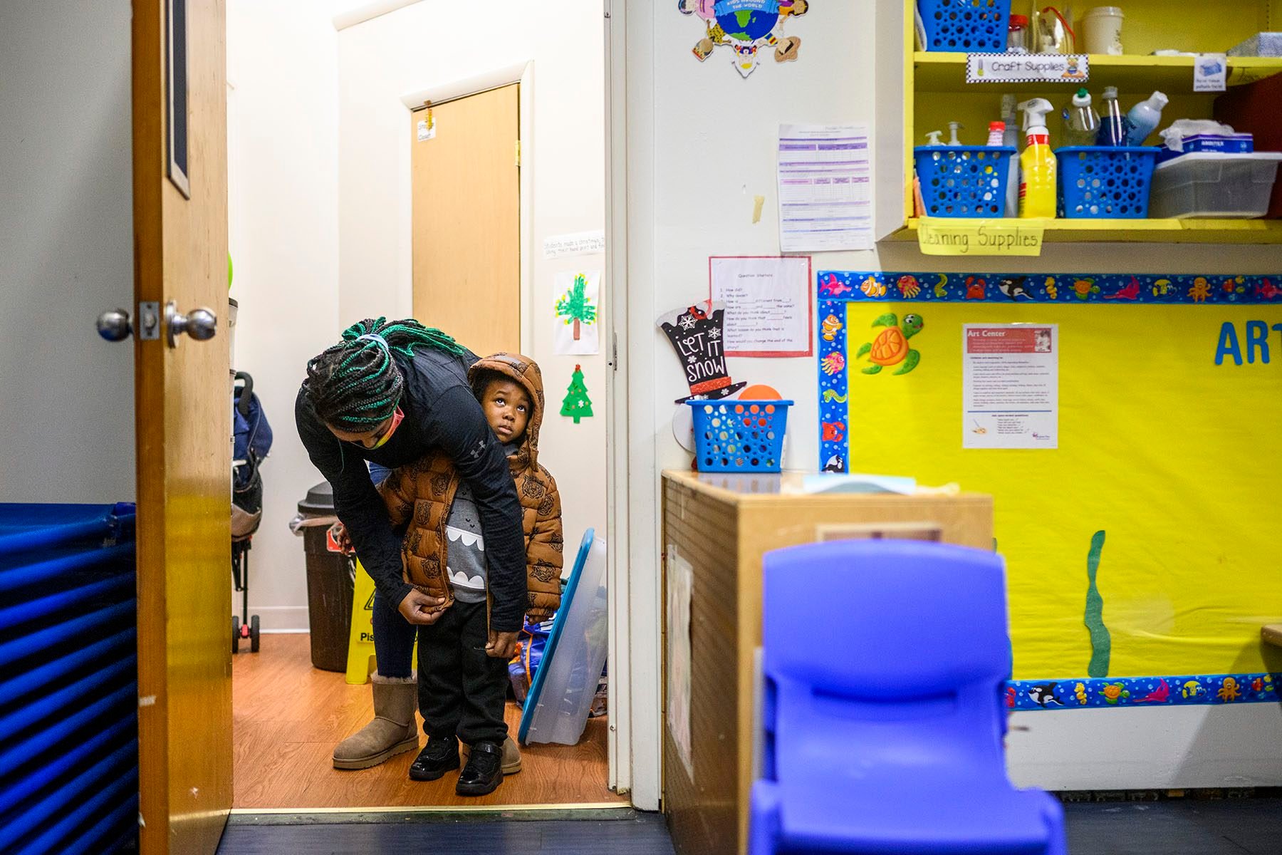 A teacher zips up a child