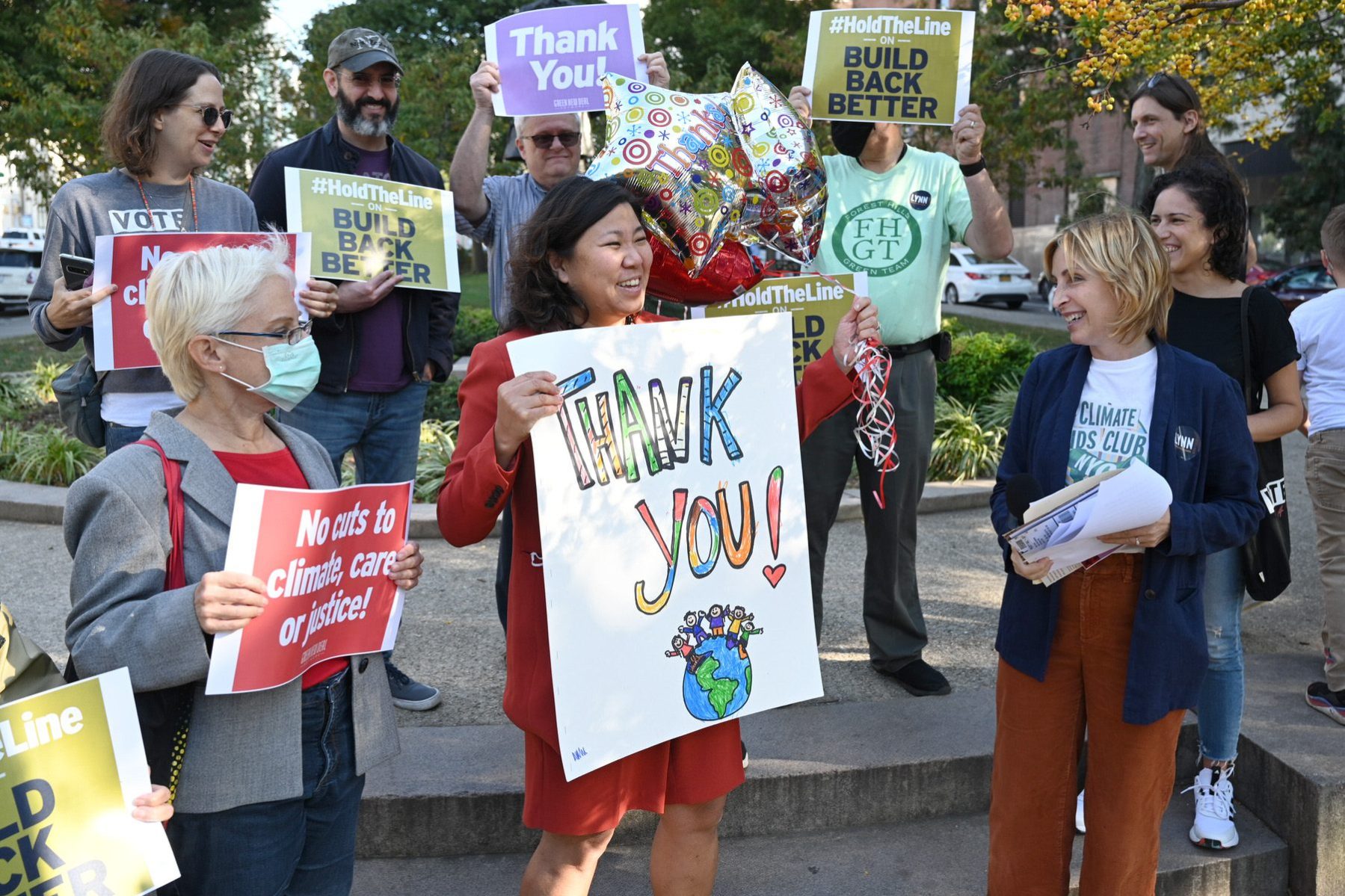 Grace Meng holds a sign that says thank you while surrounded by smiling people