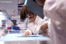 A young black woman in a lab coat is seen in a lab aboard OceanXplorer.