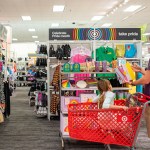 A customer with a child in their cart shops through Pride Month accessories at a Target store.