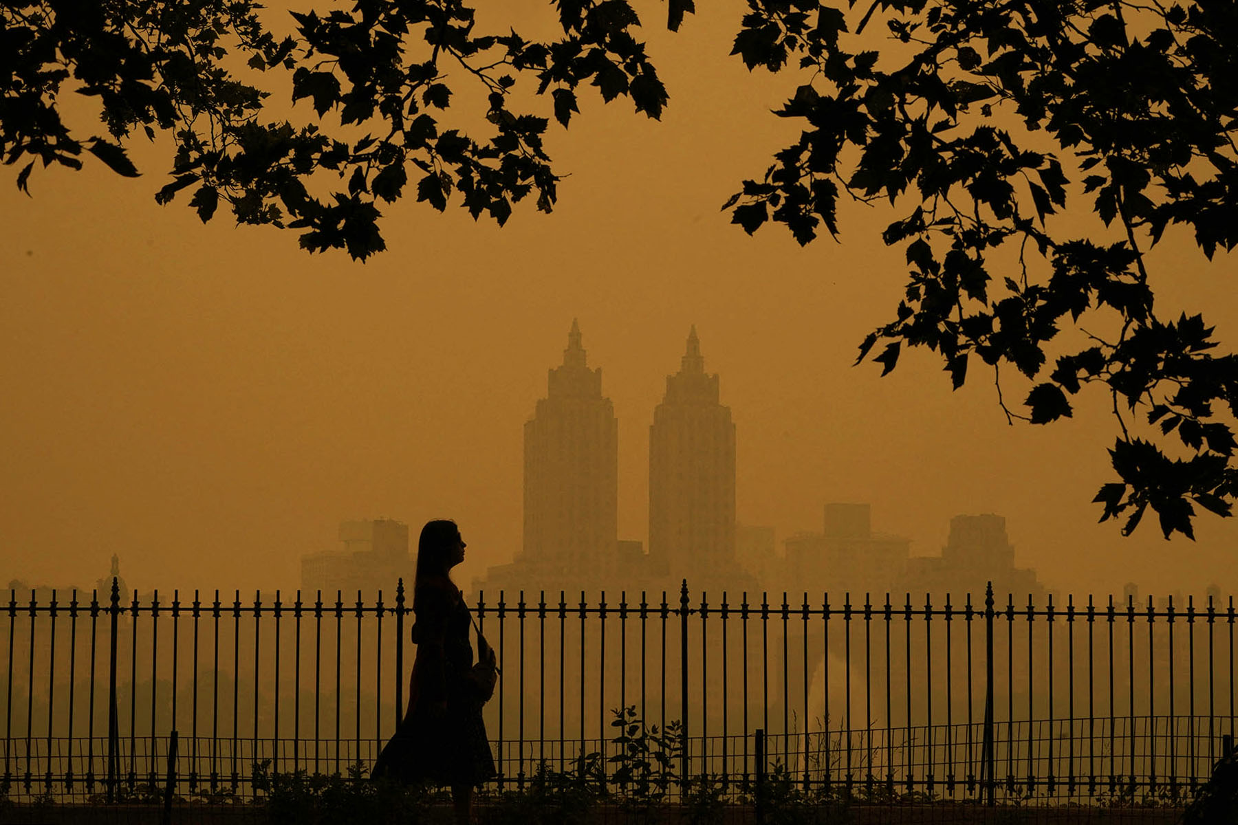 A woman walks in Central Park as smoke from wildfires in Canada cause hazy conditions.