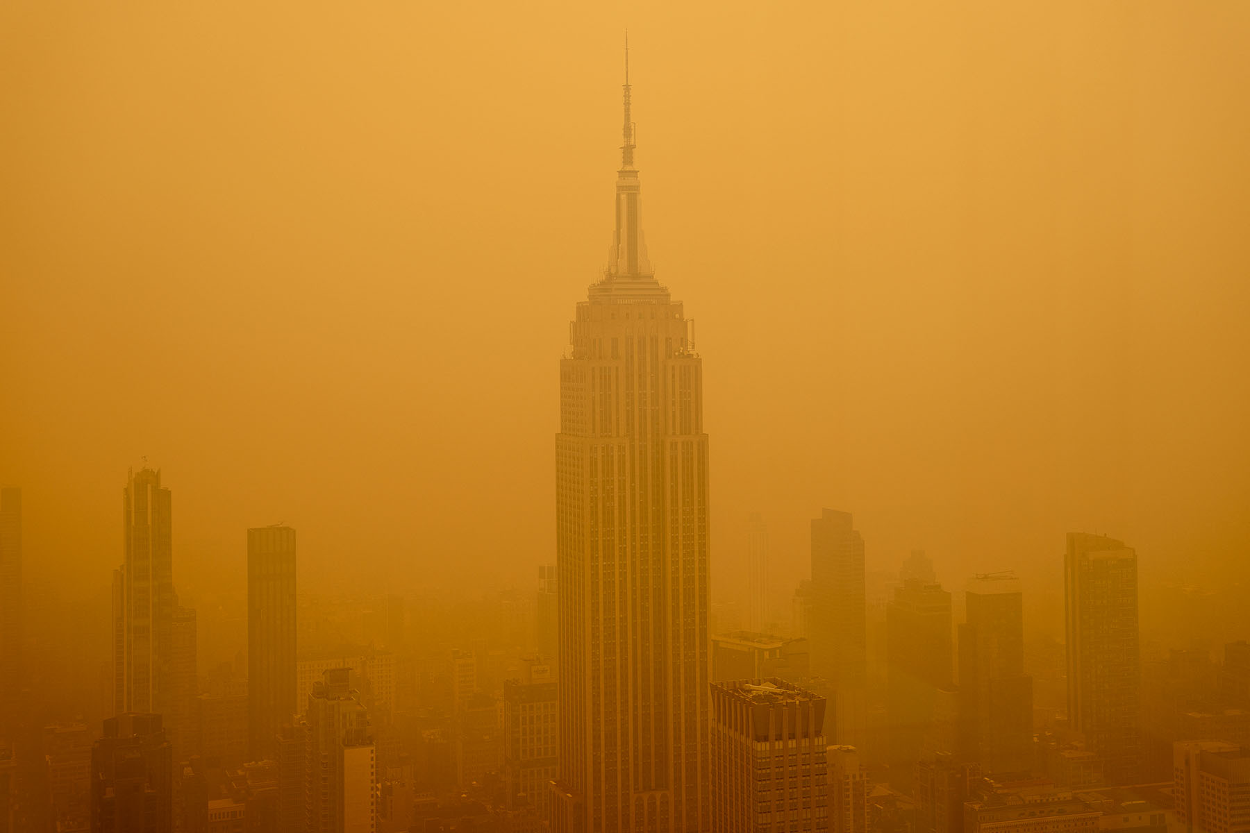 Orange smoky haze from wildfires in Canada diminishes the visibility of the Empire State Building in New York City.